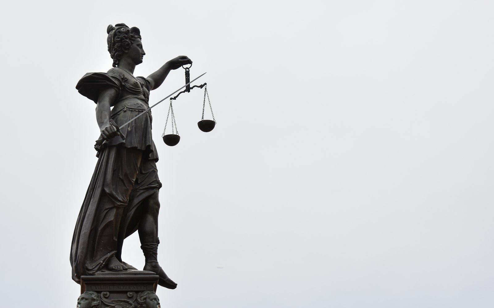 Statue of Justice holding scales against a pale sky