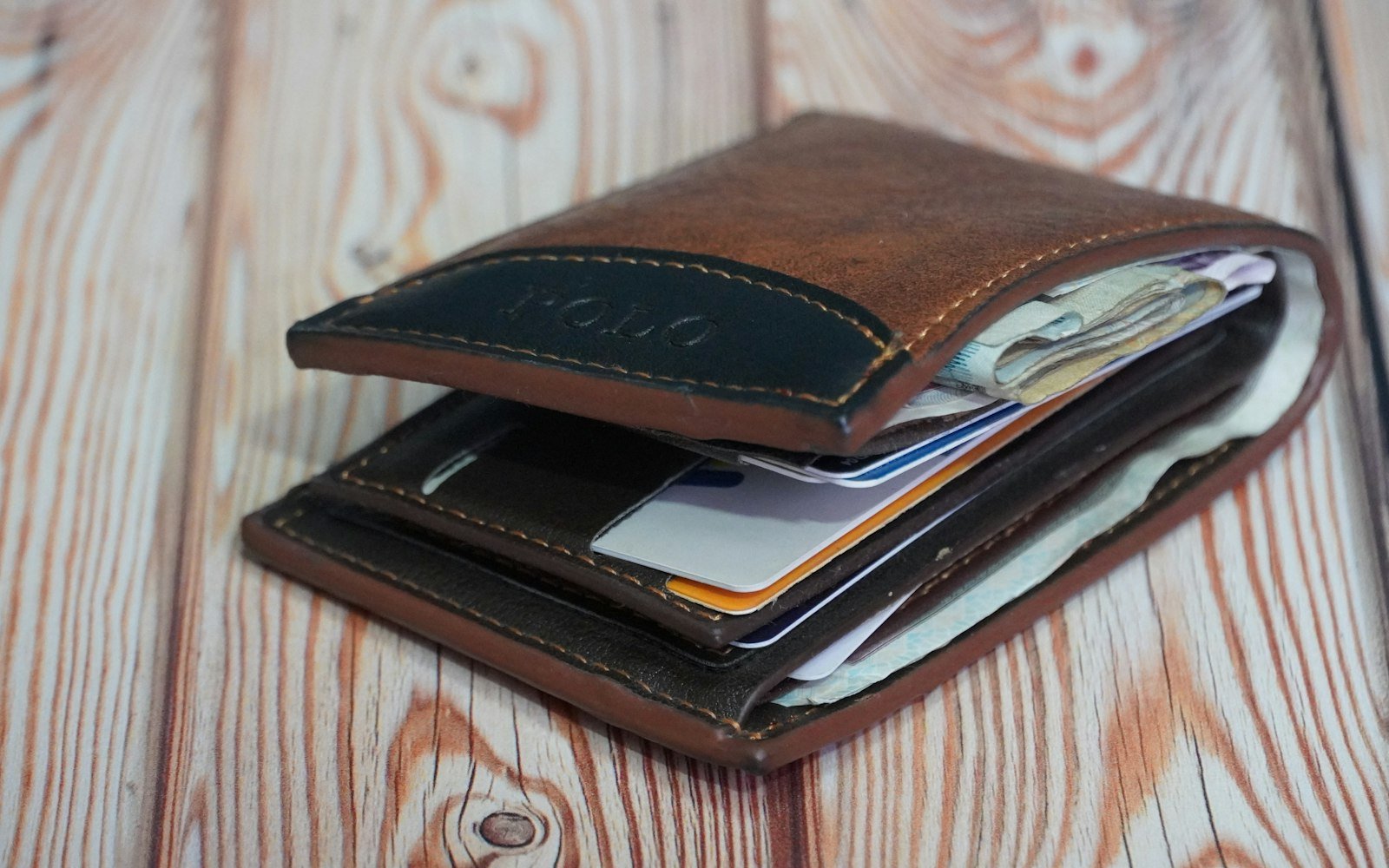 Open leather wallet with cards on a wooden table