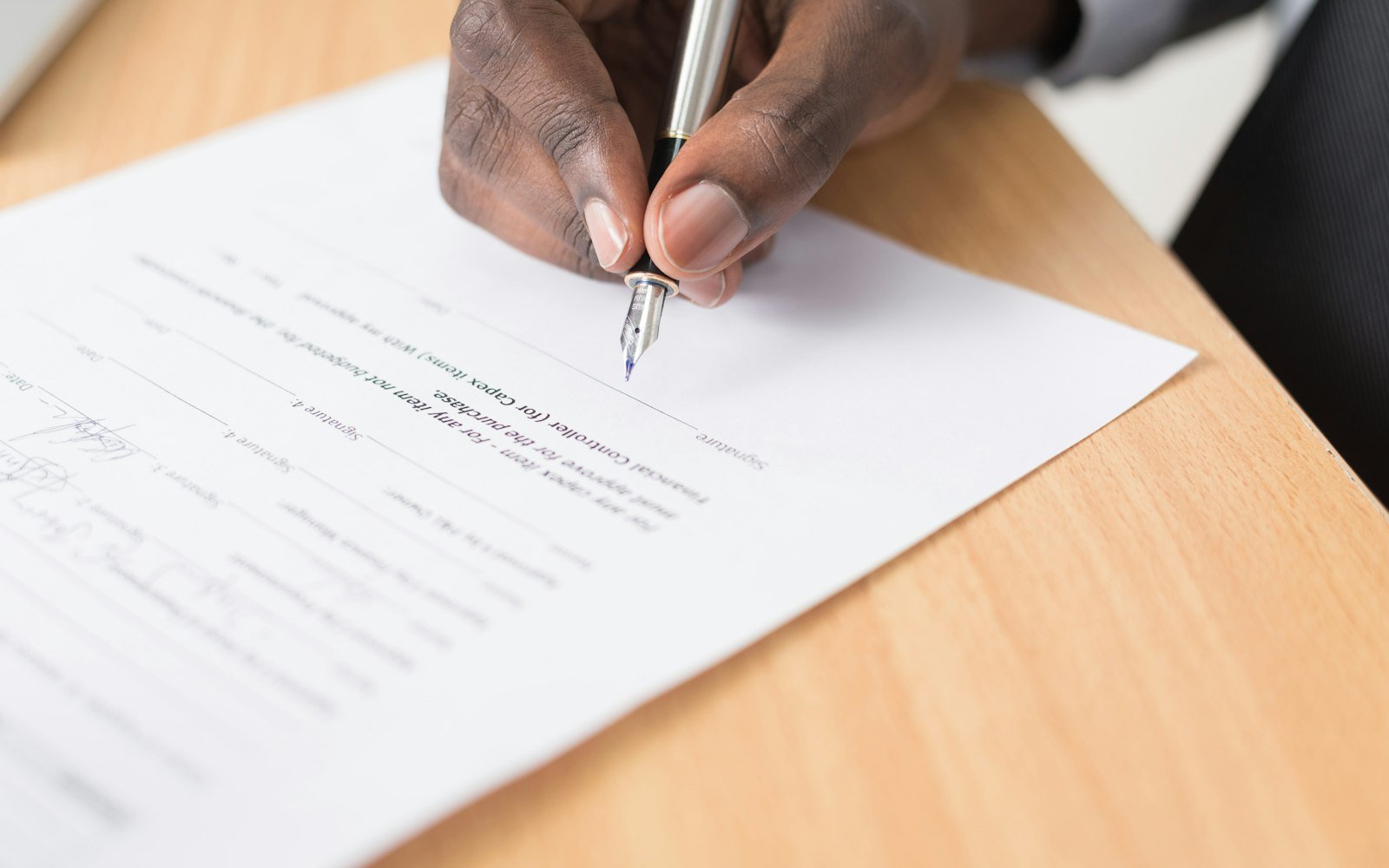 A person signing a document at a desk