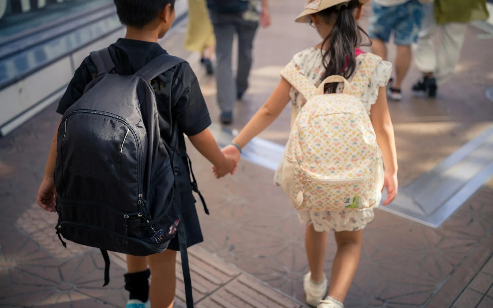 Two children with school backpacks walking hand in hand