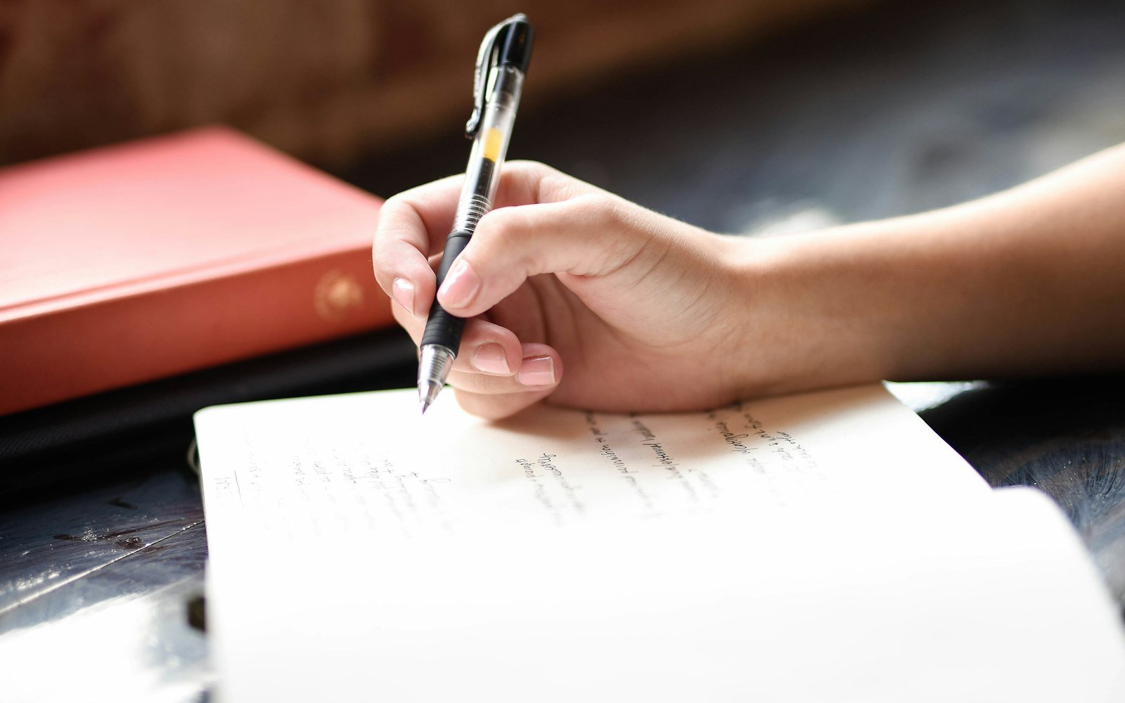A hand writing on paper with a pen