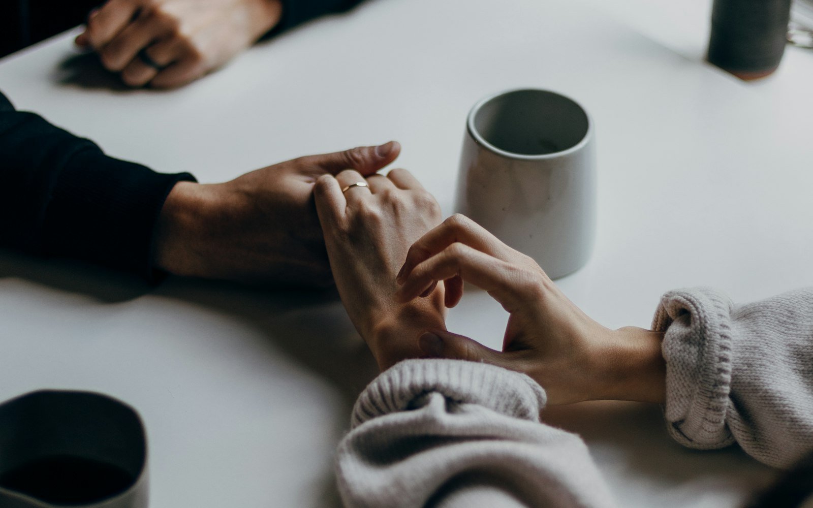 Two people holding hands across a table
