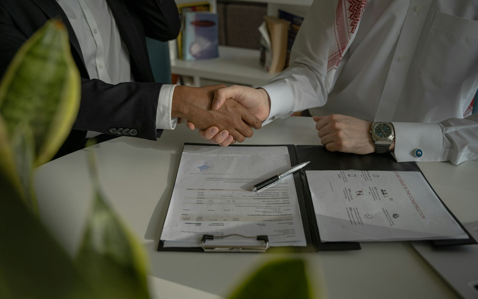 Two people shaking hands over signed papers