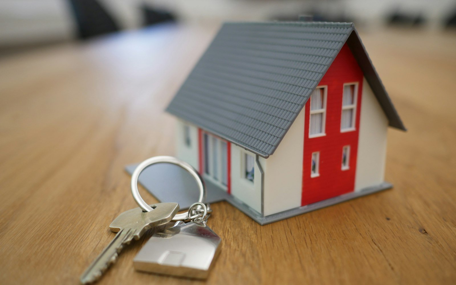 A small model house and a set of keys on a table