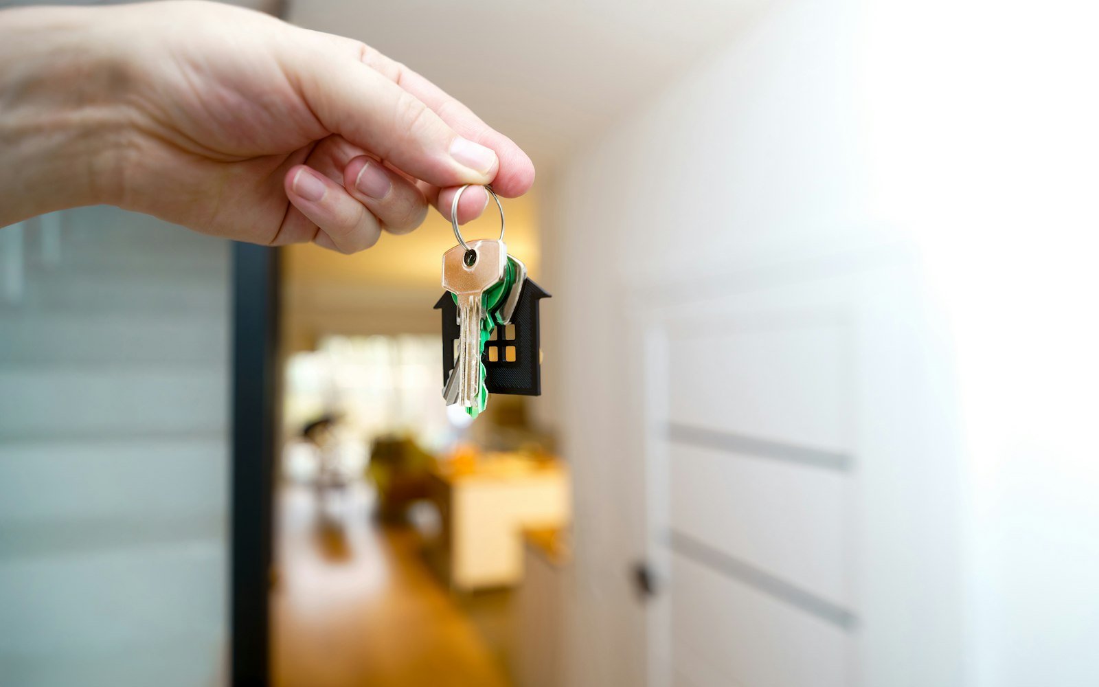 A hand holding house keys in front of an open door