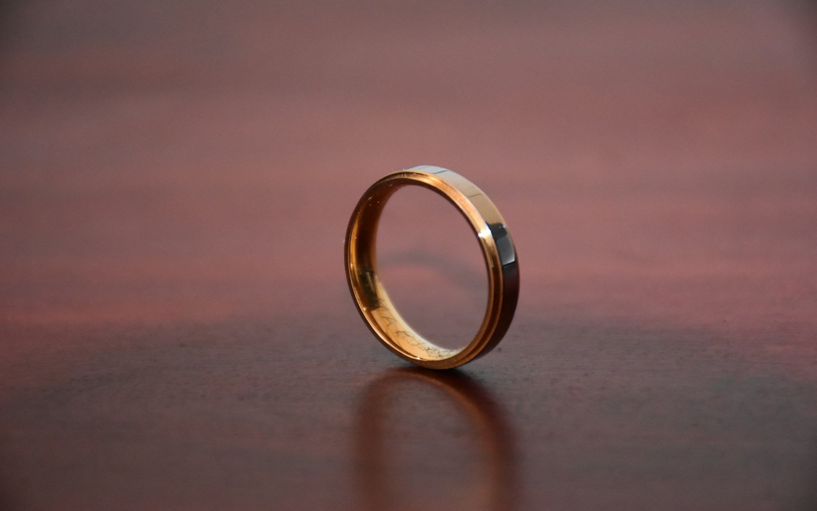 A single gold wedding ring on a wooden table