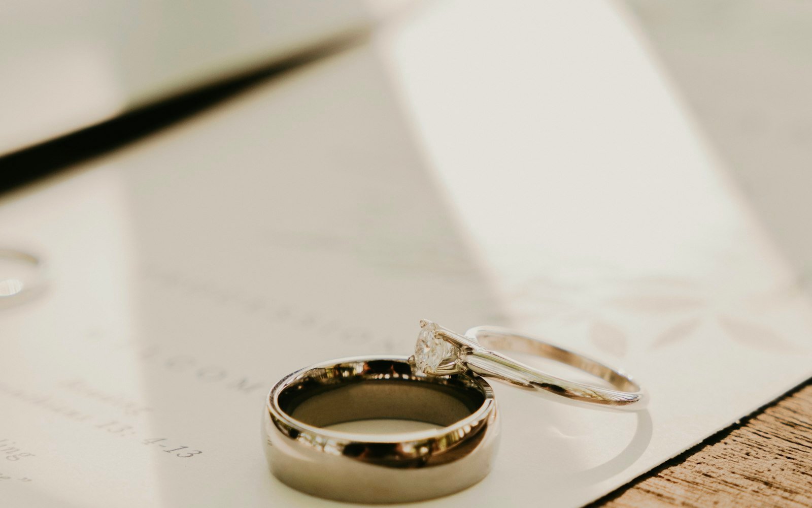 Two wedding rings resting on a document beside a pen